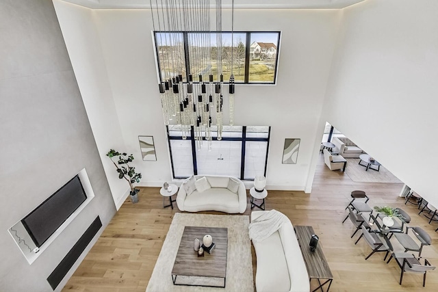 living room with a high ceiling, baseboards, and wood finished floors