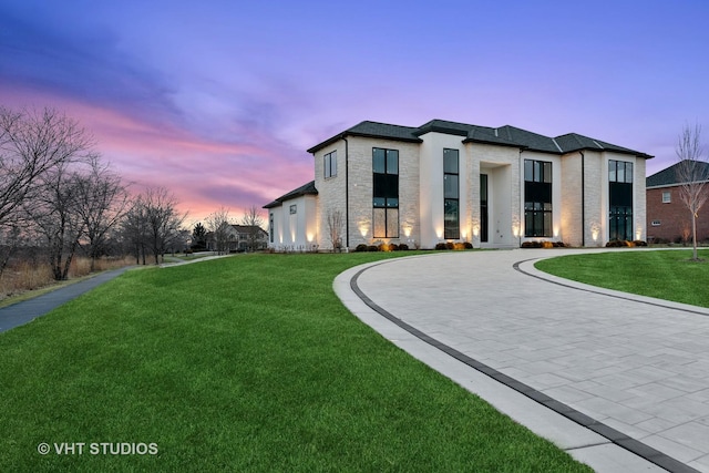 view of front facade featuring stone siding, curved driveway, and a front yard