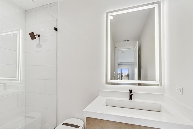 bathroom featuring vanity, visible vents, and tiled shower