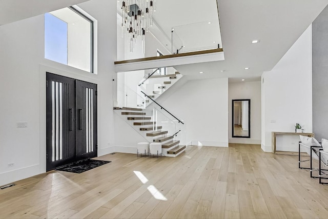 entryway featuring stairs, wood finished floors, visible vents, and a towering ceiling