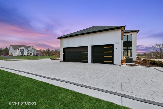 garage featuring central air condition unit and decorative driveway