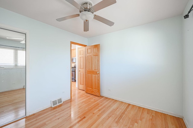 empty room featuring visible vents, baseboards, a ceiling fan, and wood finished floors