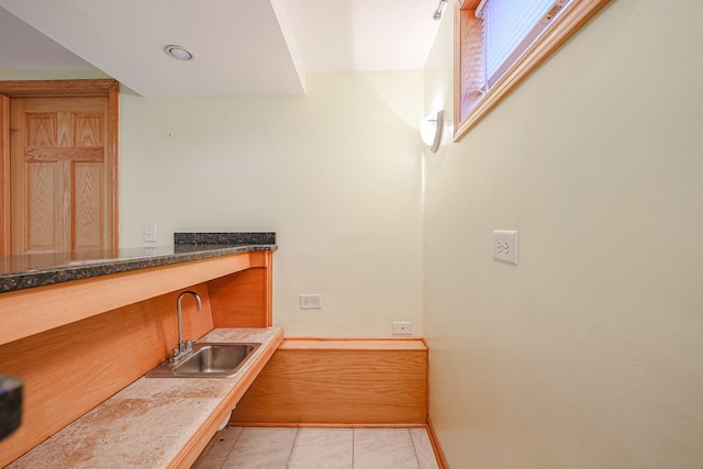 interior space featuring a sink, baseboards, and light tile patterned floors