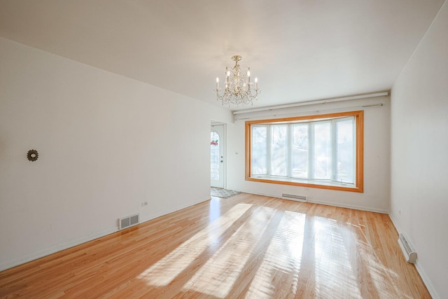 spare room featuring an inviting chandelier, visible vents, and light wood-type flooring