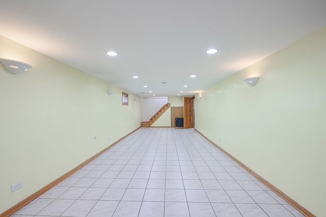 finished below grade area with light tile patterned floors, stairway, recessed lighting, and baseboards