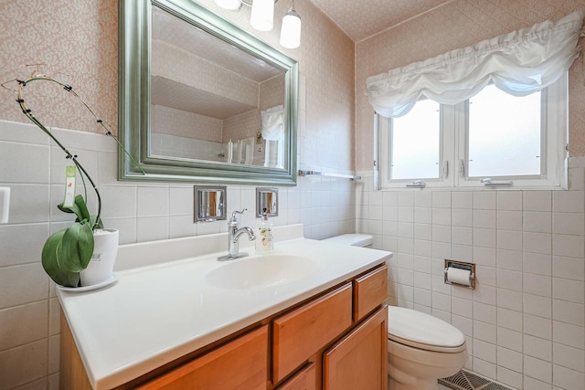 bathroom with tile walls, toilet, wallpapered walls, and vanity