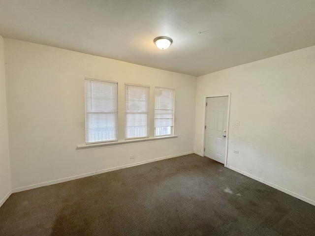 spare room with dark colored carpet and baseboards