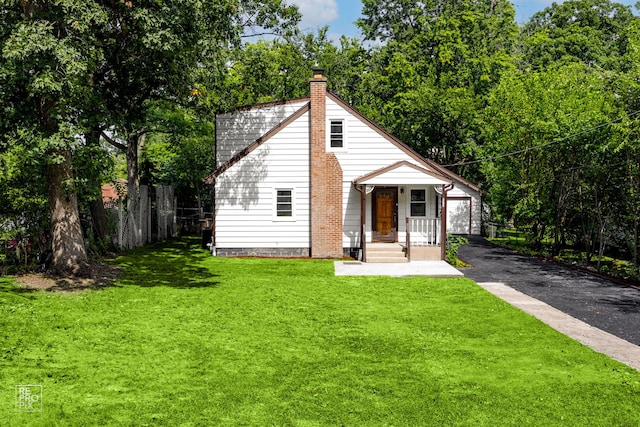 view of front of home with an outbuilding, fence, a front lawn, and a chimney