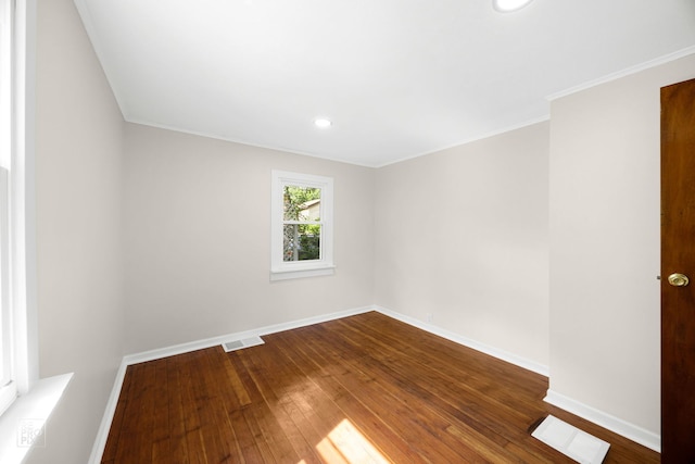 empty room featuring visible vents, baseboards, dark wood-style flooring, and ornamental molding