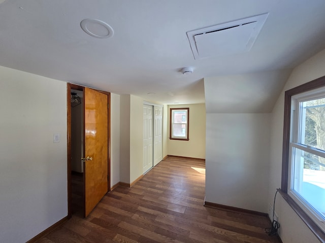 hallway with dark wood-style floors, attic access, baseboards, and vaulted ceiling