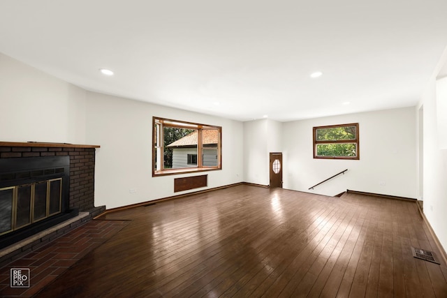 unfurnished living room with visible vents, a brick fireplace, baseboards, and hardwood / wood-style flooring