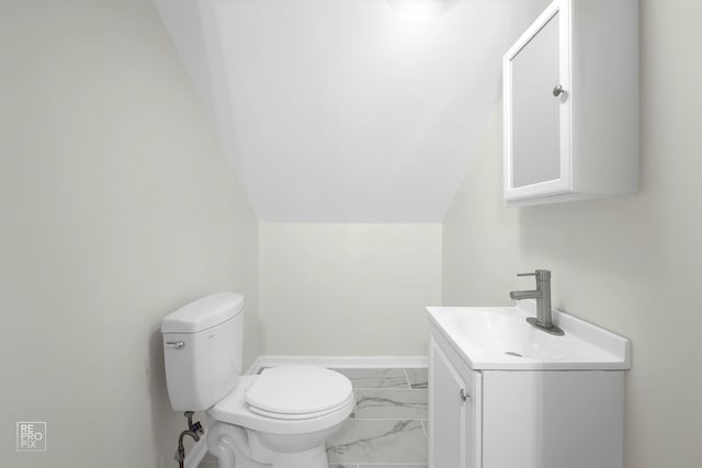 half bath featuring baseboards, toilet, vaulted ceiling, marble finish floor, and vanity