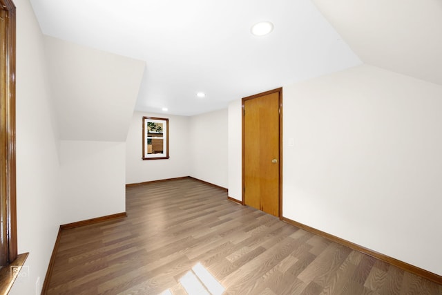 additional living space with recessed lighting, light wood-type flooring, baseboards, and vaulted ceiling