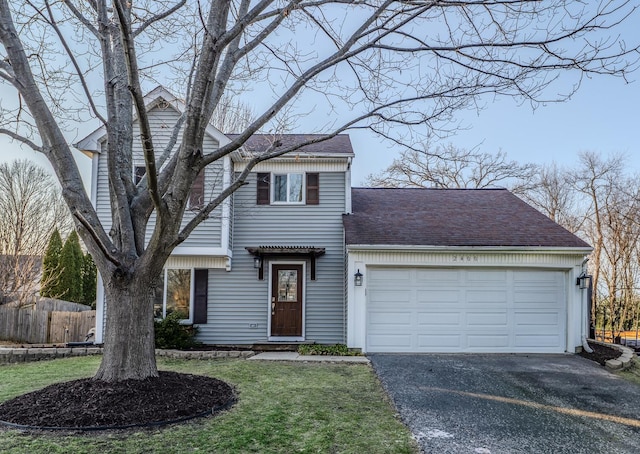 traditional home with a shingled roof, a front lawn, fence, aphalt driveway, and a garage