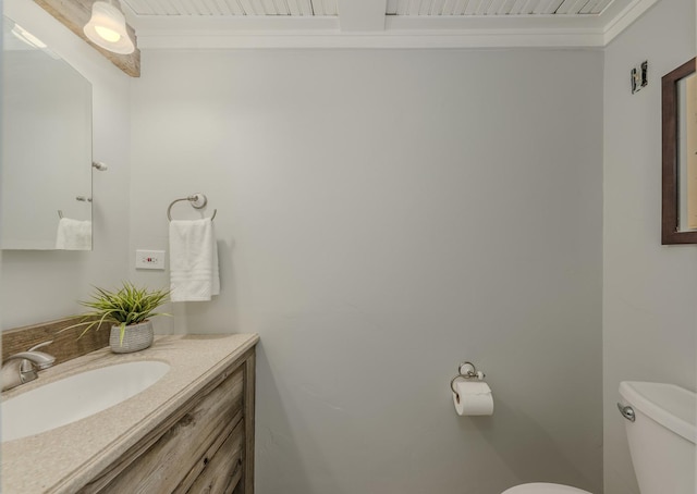 bathroom with toilet, vanity, and ornamental molding