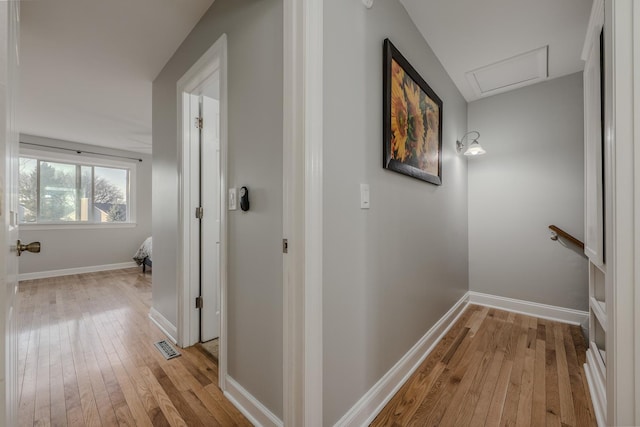 corridor with visible vents, light wood-style flooring, and baseboards