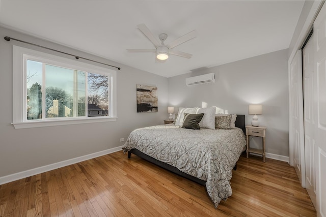 bedroom featuring a wall mounted air conditioner, a closet, baseboards, and hardwood / wood-style flooring