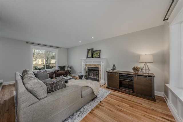 living room featuring recessed lighting, light wood-type flooring, baseboards, and a tiled fireplace