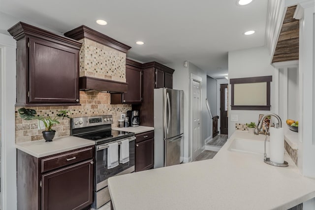 kitchen featuring dark brown cabinetry, light countertops, decorative backsplash, stainless steel appliances, and a sink