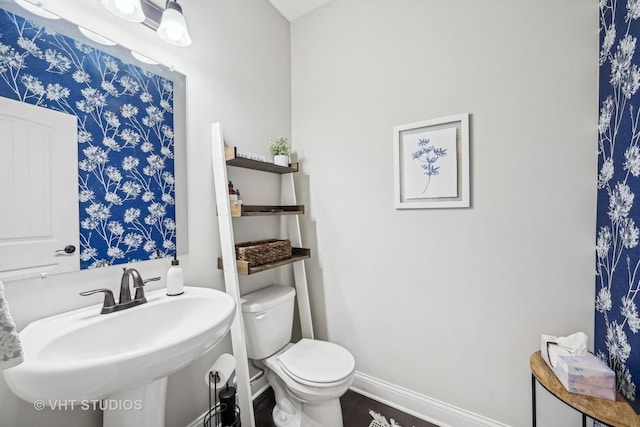 bathroom with toilet, baseboards, and a sink