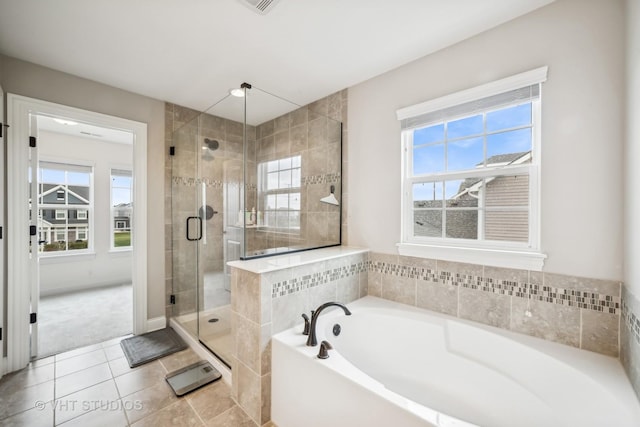 bathroom with tile patterned floors, a healthy amount of sunlight, a stall shower, and a garden tub