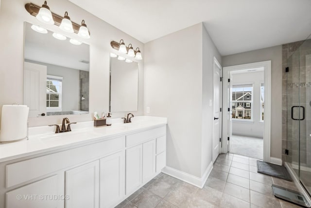 bathroom with a sink, baseboards, a stall shower, and double vanity