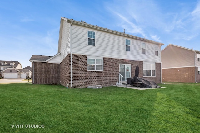 back of property featuring a yard, a patio area, and brick siding