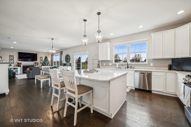 kitchen with tasteful backsplash, dark wood finished floors, pendant lighting, appliances with stainless steel finishes, and white cabinets