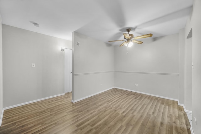 spare room with wood finished floors, a ceiling fan, and baseboards