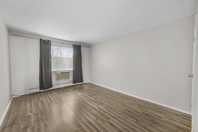 spare room with a baseboard heating unit, wood finished floors, and baseboards