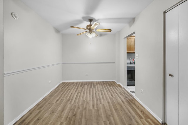 interior space featuring light wood-type flooring, baseboards, and ceiling fan