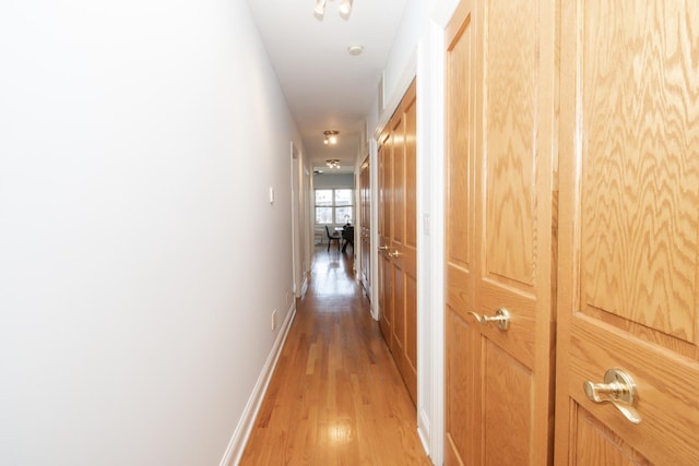 corridor featuring baseboards and light wood-style flooring