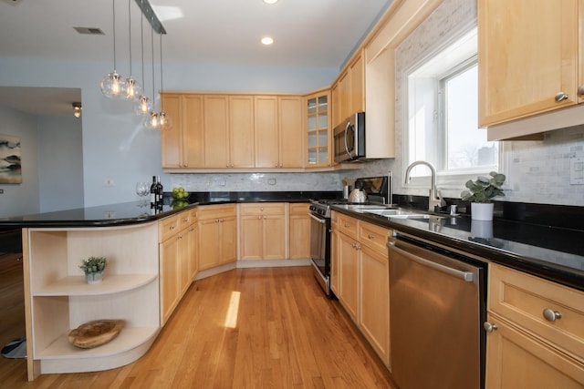 kitchen with dark countertops, light brown cabinets, open shelves, stainless steel appliances, and a sink