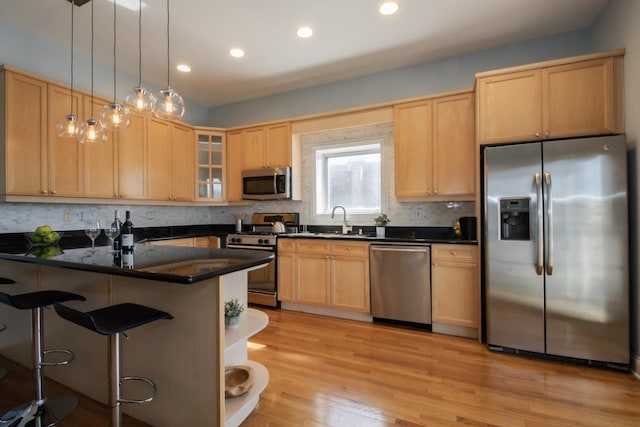 kitchen with glass insert cabinets, light brown cabinetry, a breakfast bar, a peninsula, and stainless steel appliances