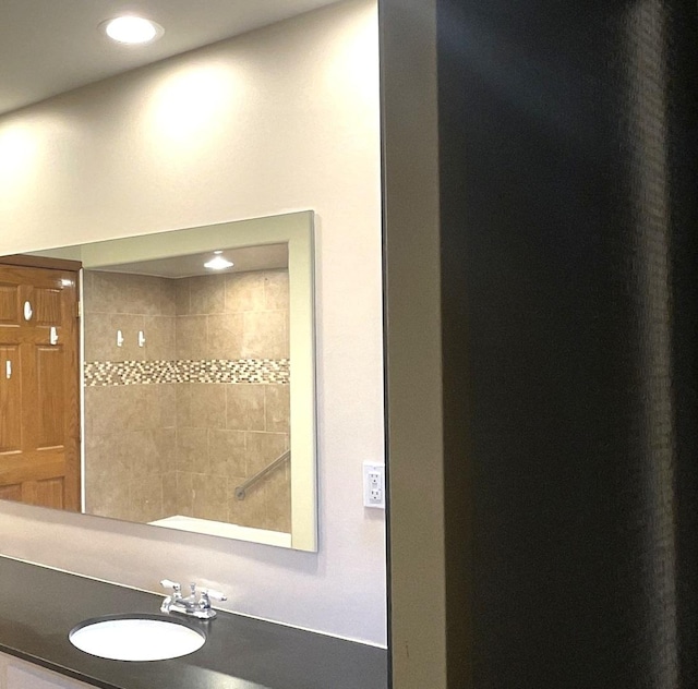 bathroom featuring a sink, tiled shower, and recessed lighting