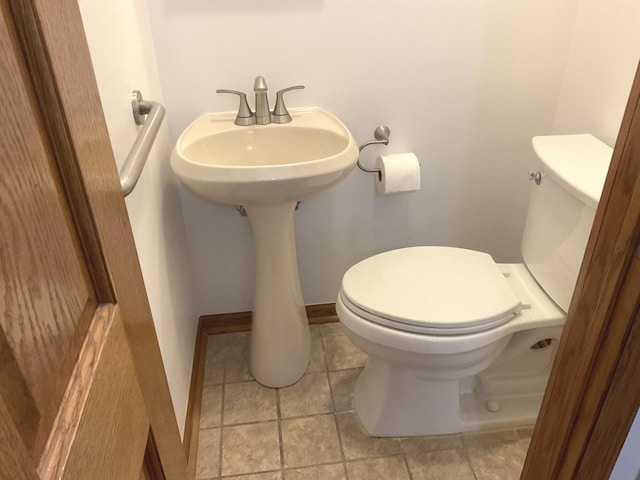 half bath featuring baseboards and toilet