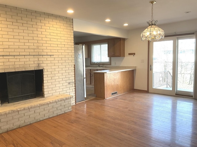 kitchen with a sink, light countertops, freestanding refrigerator, and wood finished floors