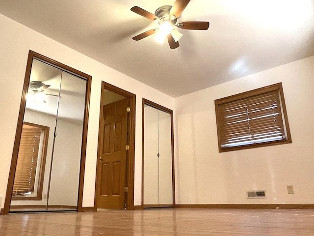 interior space featuring visible vents, ceiling fan, baseboards, and multiple closets