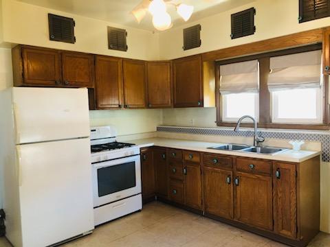 kitchen with a sink, visible vents, white appliances, and light countertops