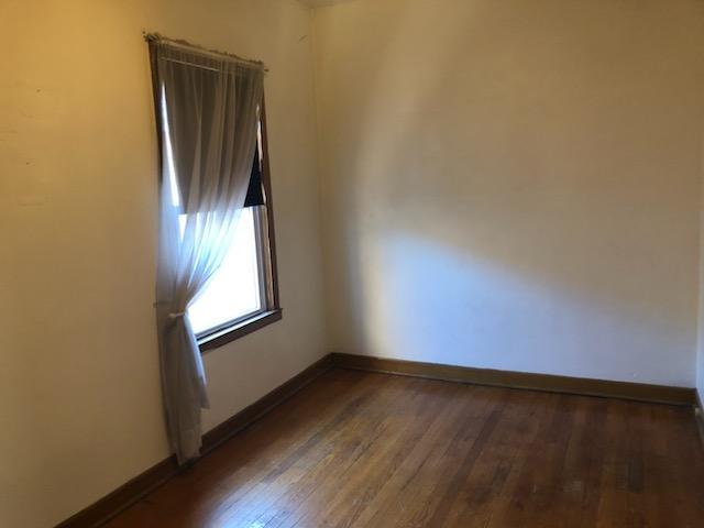 empty room with baseboards and wood-type flooring