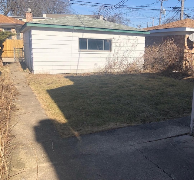 view of side of home featuring a lawn, fence, and a shingled roof