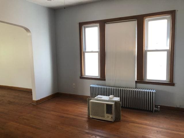 empty room featuring radiator heating unit, wood finished floors, and baseboards