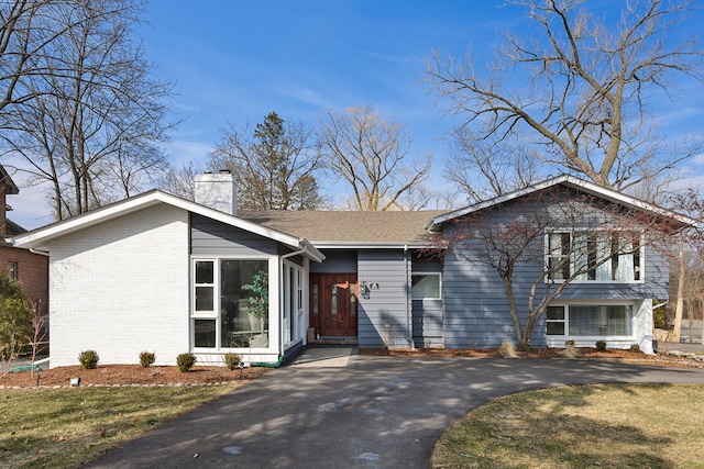 view of front of property featuring a front lawn, driveway, and a chimney