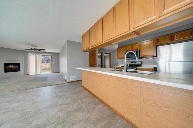 kitchen with a ceiling fan, visible vents, stainless steel appliances, light countertops, and open floor plan