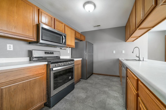 kitchen featuring visible vents, brown cabinets, a sink, appliances with stainless steel finishes, and light countertops