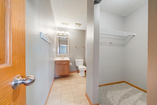 bathroom featuring visible vents, baseboards, toilet, vanity, and a textured ceiling