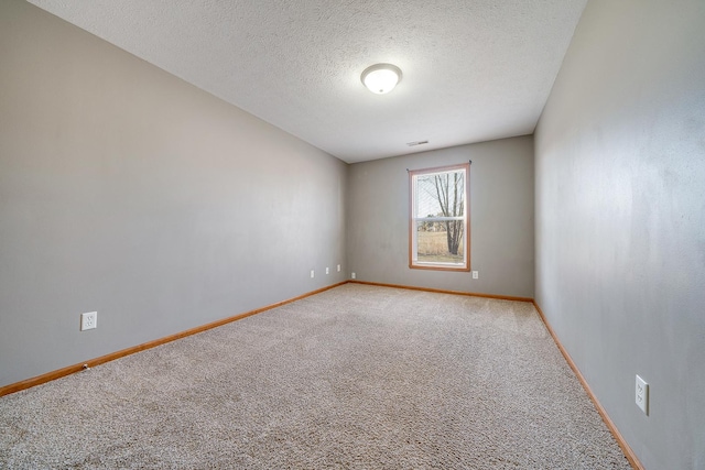 unfurnished room with visible vents, light colored carpet, a textured ceiling, and baseboards