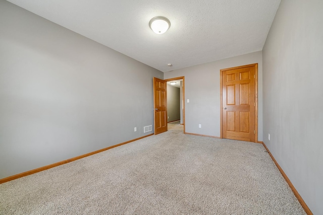 unfurnished bedroom featuring light colored carpet, baseboards, visible vents, and a textured ceiling