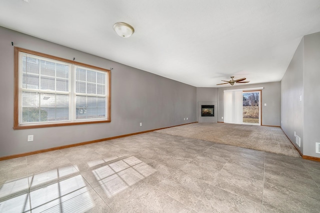 unfurnished living room with baseboards, a fireplace, and a ceiling fan