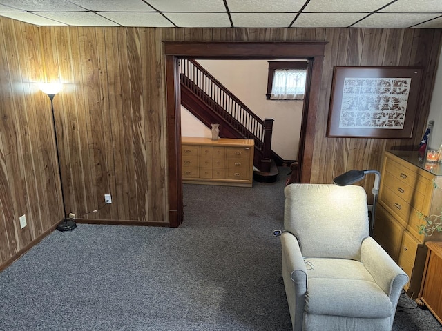 sitting room featuring stairway, a paneled ceiling, wood walls, and carpet floors